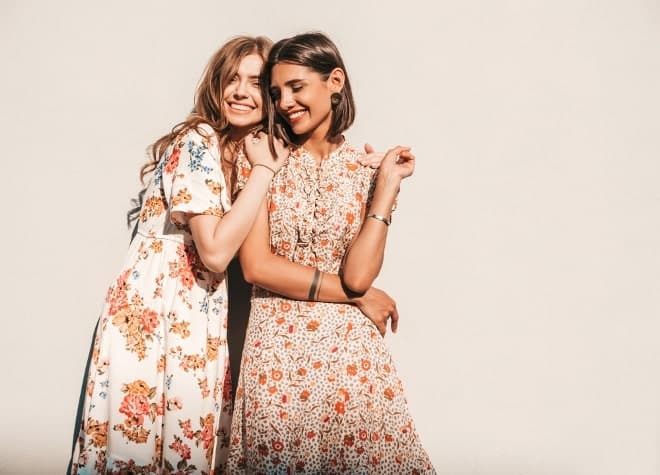 Dos amigas abrazadas con vestidos largos floreados