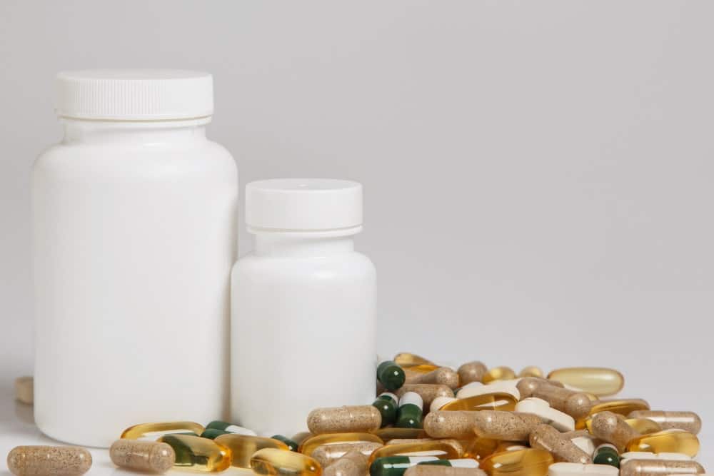 Frascos blancos y cápsulas de suplementos sobre una mesa