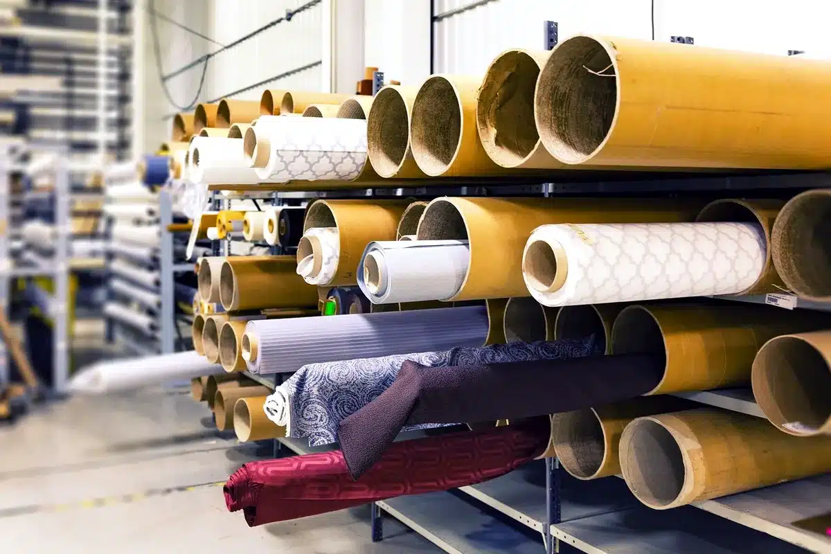 Rollos de tela apilados en estanterías de un almacén textil